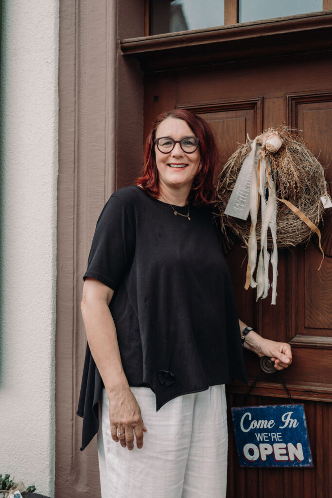 Franziska Steiner, die Inhaberin, steht vor einer Tür und zeigt ein freundliches Lächeln.